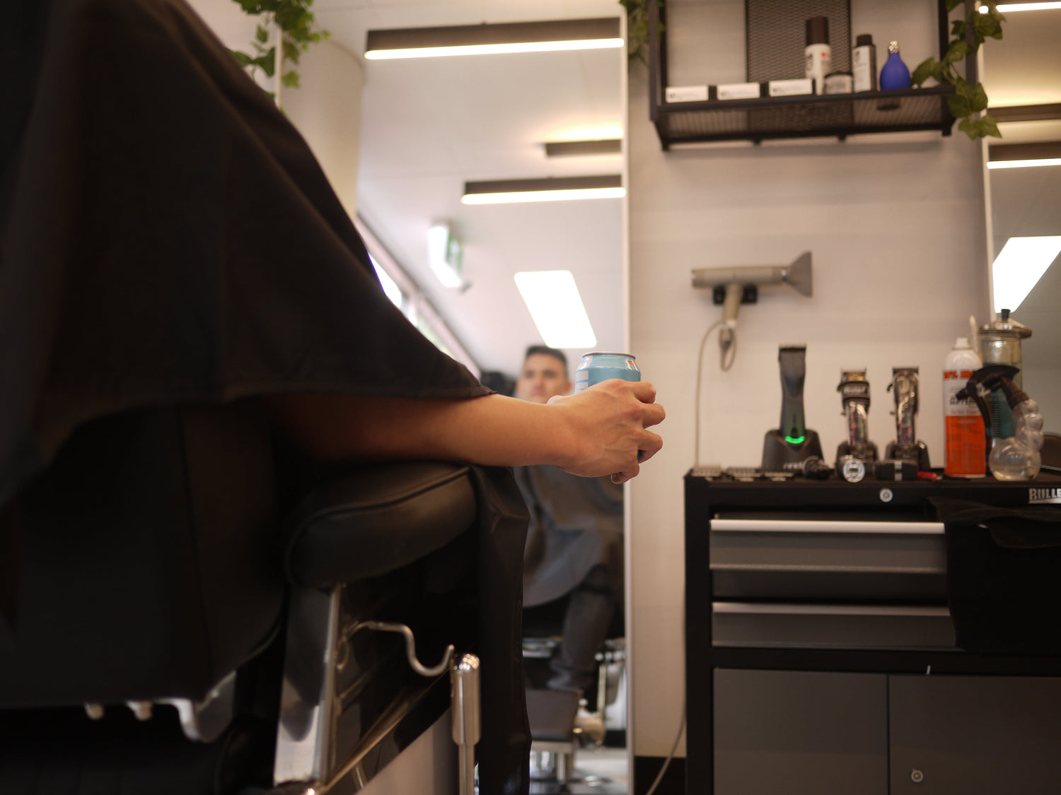 Barbershop client getting haircut with beer